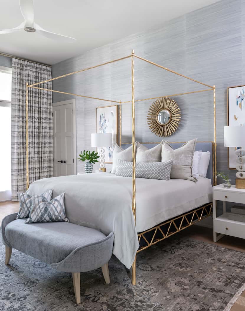 A bedroom with blue wallpaper and a gold starburst mirror.