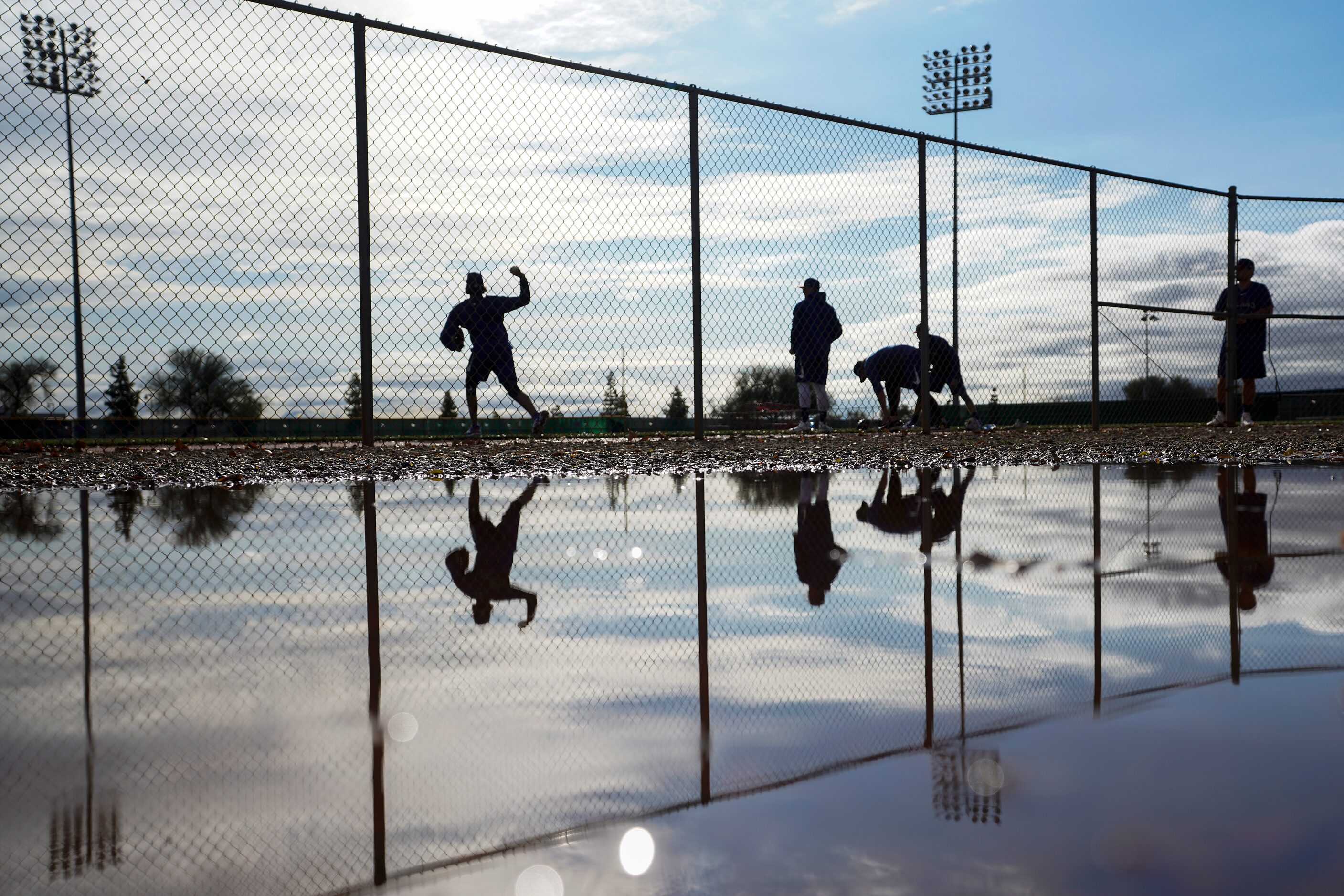 Texas Rangers pitcher Tyler Phillips is reflected in a puddle left by overnight rain as he...