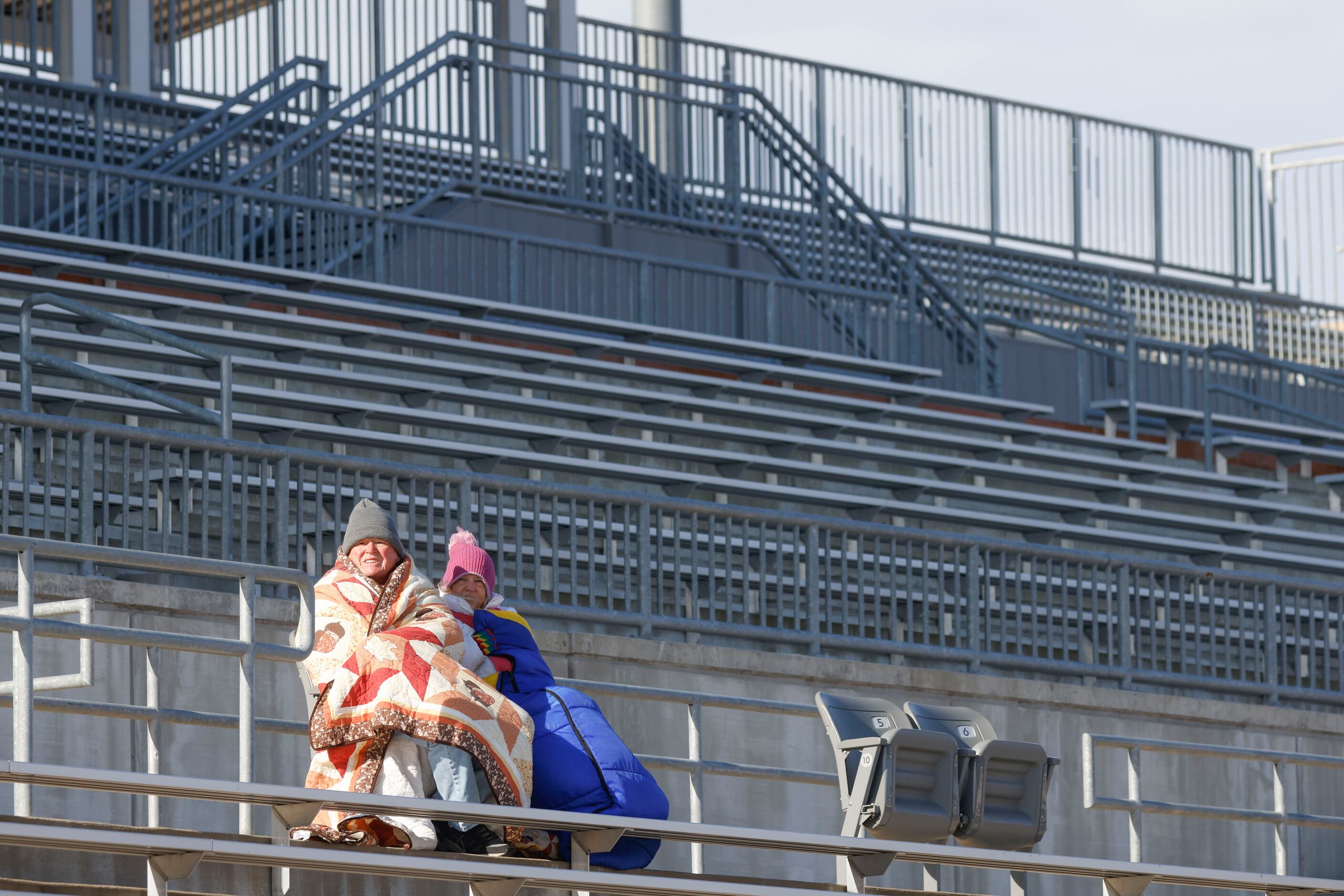 People wearing warm clothes watch a soccer game between South Grand Prairie High School and...