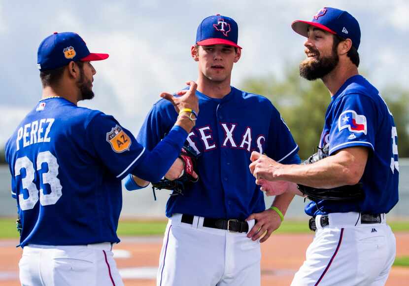 Minor league pitcher Cole Ragans, center, gets advice from starting pitcher Martin Perez...