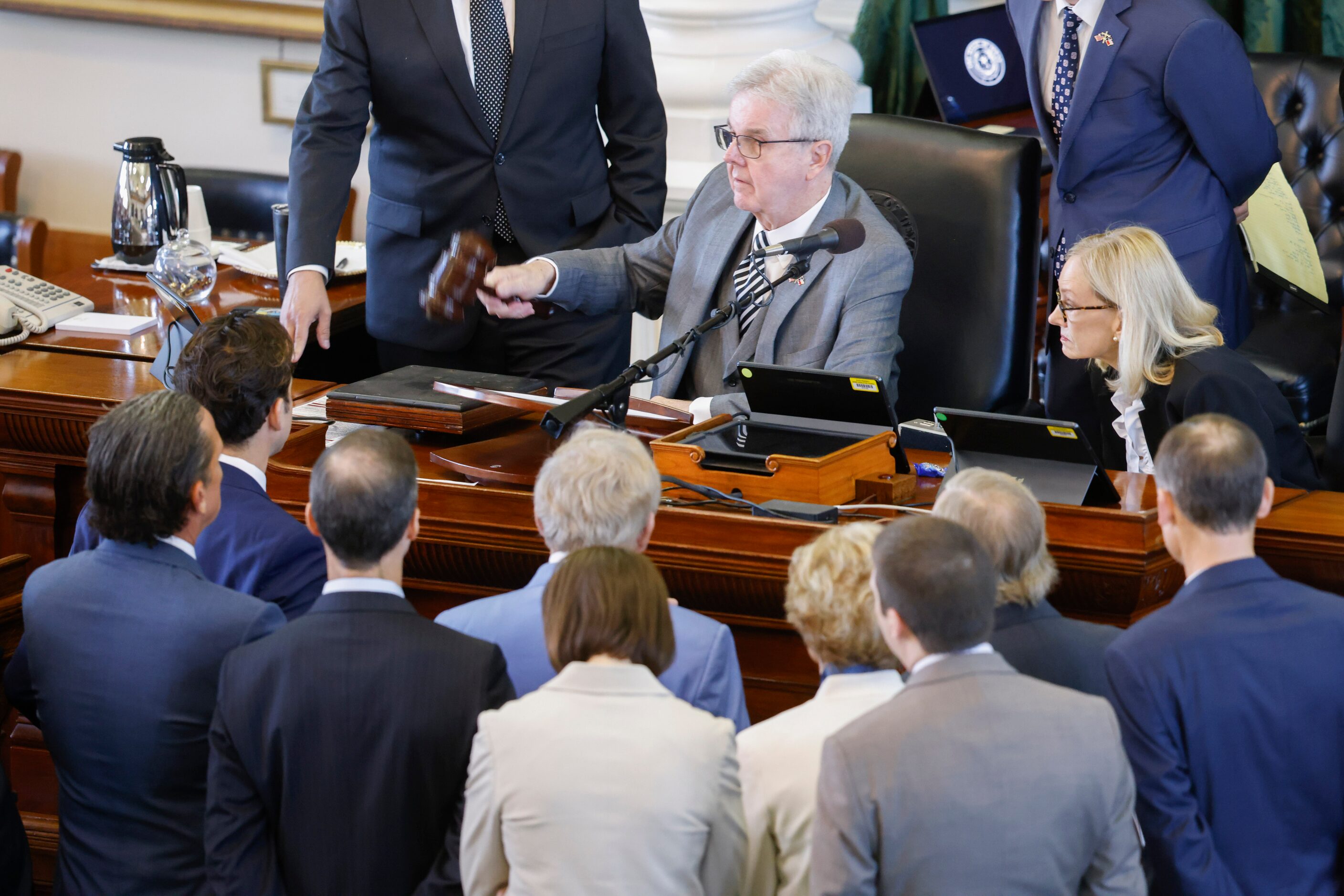 Lt. Gov. Dan Patrick (center) bangs his gavel while conferring with defense and prosecution...