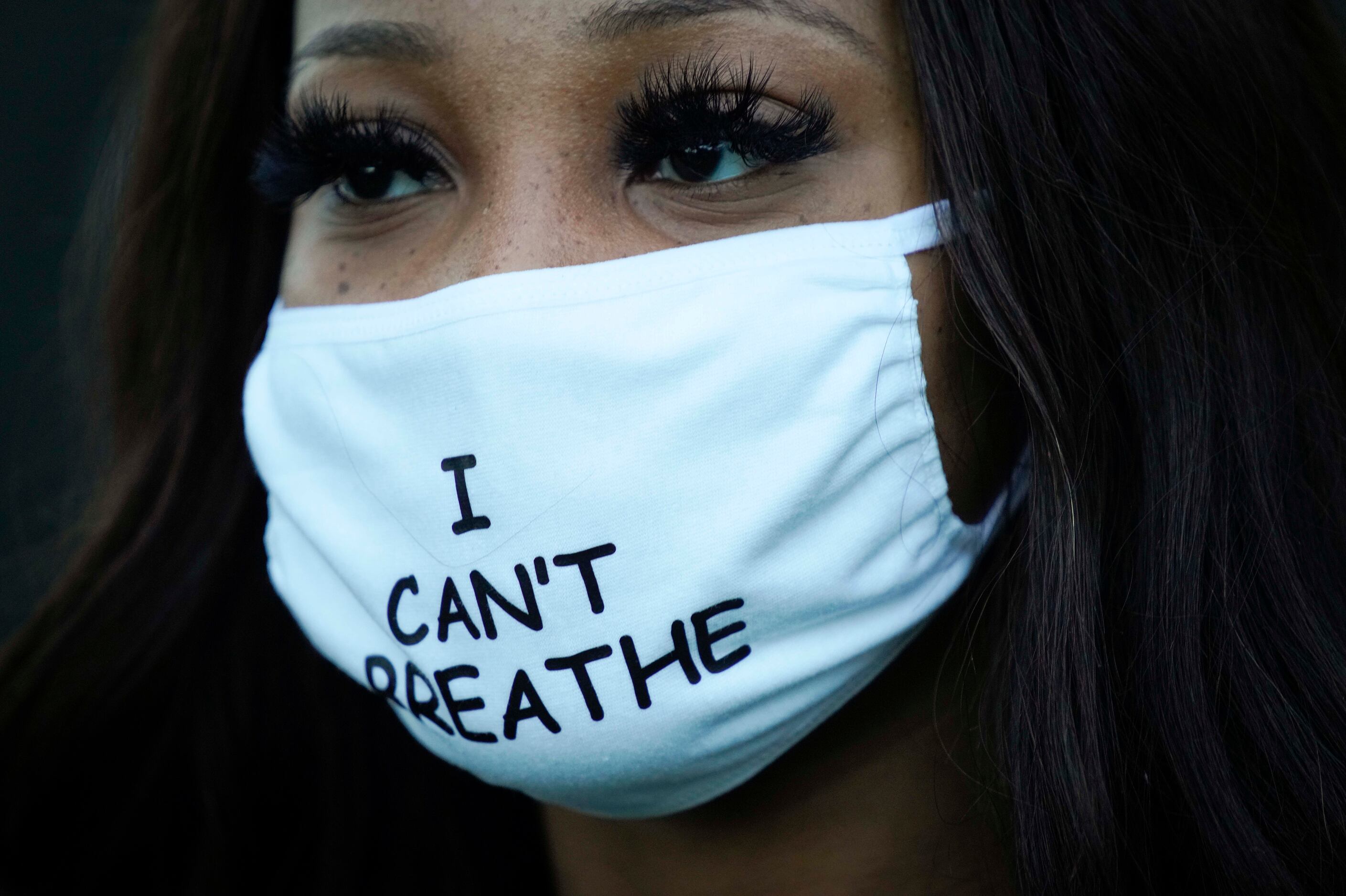A woman wears a face mask reading "I Can't Breathe" during a protest at MLK Center as...