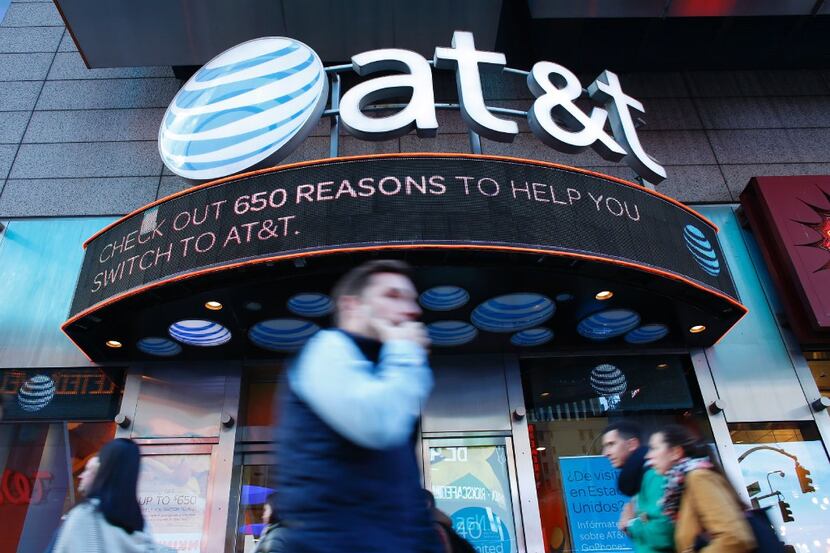 People walk past an AT&T store in New York on October 23, 2016. 
AT&T unveiled a mega-deal...