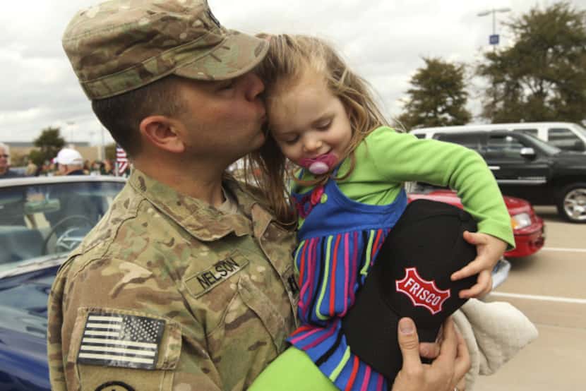 U.S. Army Capt. Tim Nelson kisses 3-year-old Elise Nelson at the parade.