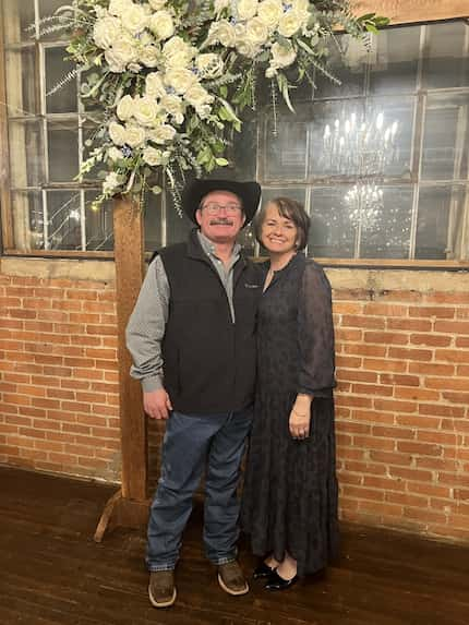 Man and woman pose together in front of a brick wall.