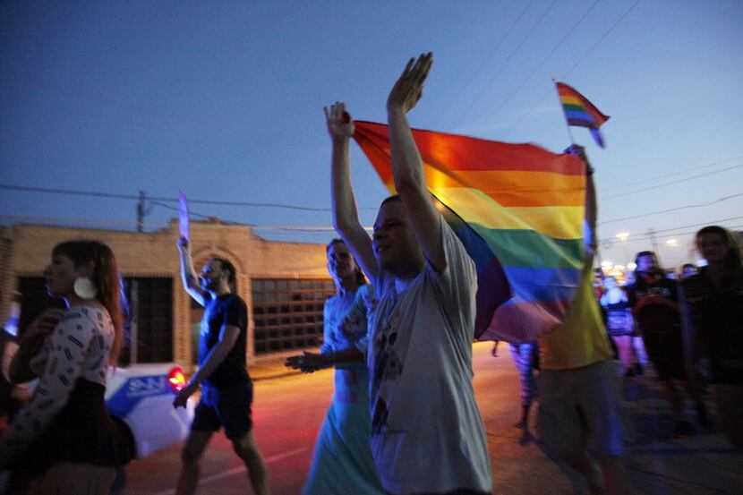 Michael Smith, 27, of Dallas, claps his hands while raising a gay pride flag during...