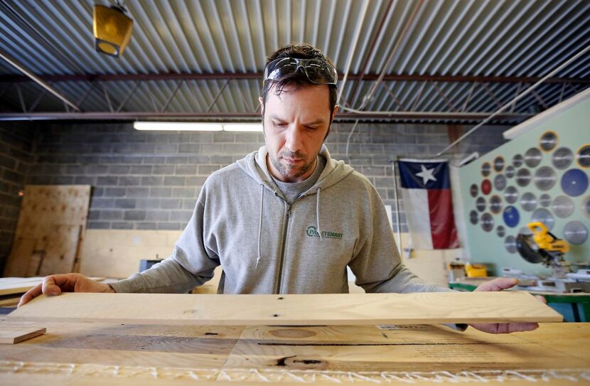 
Kevin Rennels secures a wood plank, from recycled and donated pallets, to a plywood base at...