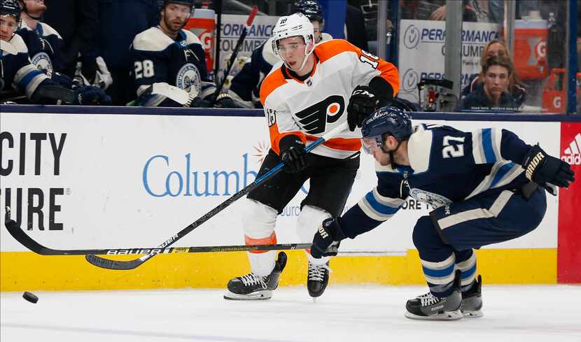 Philadelphia Flyers' Tyler Pitlick, left, dumps the puck past Columbus Blue Jackets' Ryan...