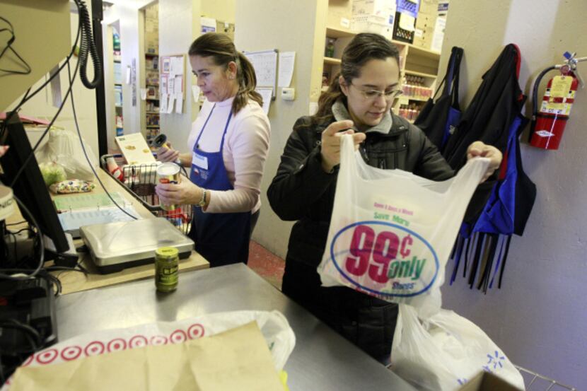 Anna Neal of Frisco, right, gets help from volunteer Sara Lempke as she checks out at the...
