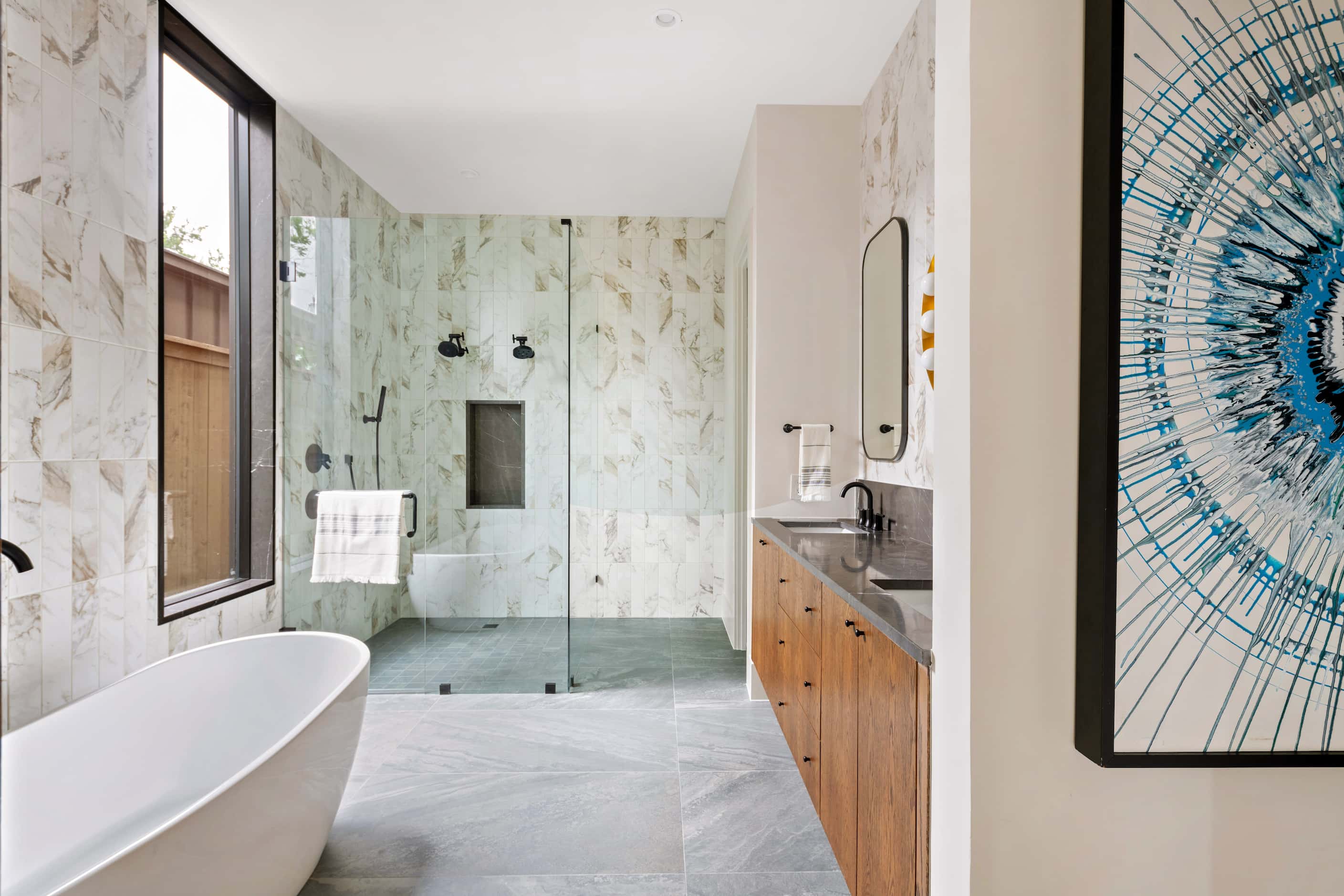 Primary bathroom with separate bathtub and shower, wood cabinetry and gray countertops