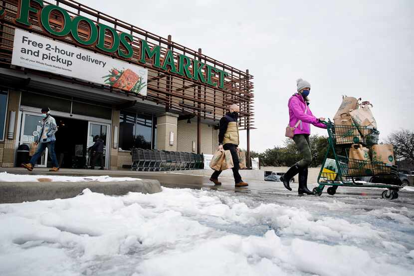 Shoppers push heir carts through the slush at Whole Foods Market in the Lakewood area of...