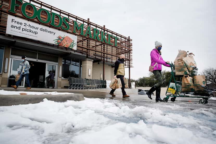 Shoppers push heir carts through the slush at Whole Foods Market in the Lakewood area of...