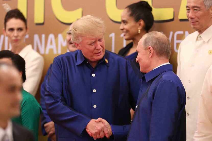 President Donald Trump (L) shakes hands with Russia's President Vladimir Putin (R) as they...