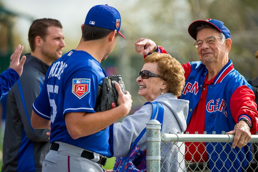 Fans Shirley Kost (center) and her husband Cal Kost (right) wave to Texas Rangers starting...