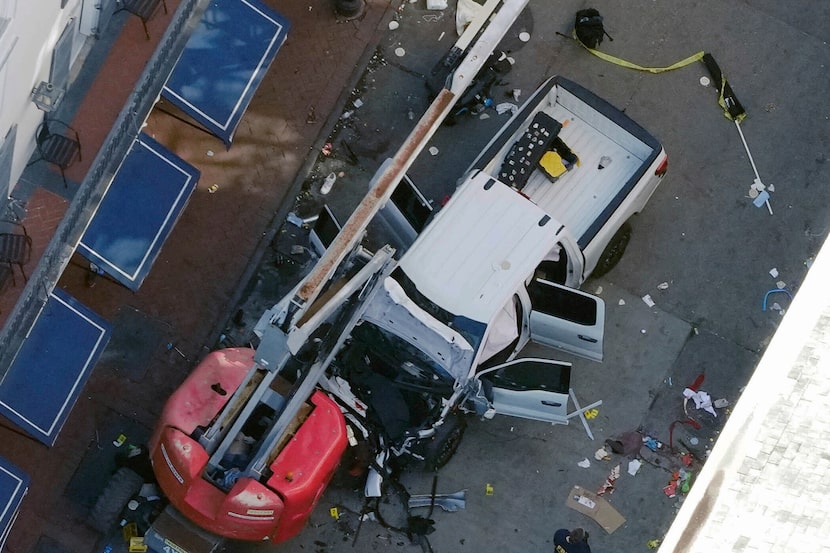 A black flag with white lettering lies on the ground behind a pickup truck that a man drove...