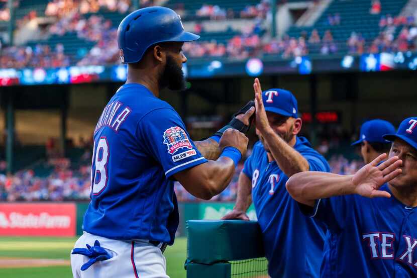 Texas Rangers first baseman Danny Santana celebrates with manager Chris Woodward and bench...