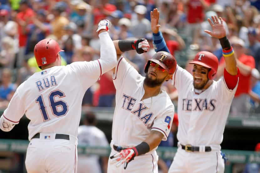 Texas Rangers' Ryan Rua is congratulated by teammates Rougned Odor, center, and Robinson...