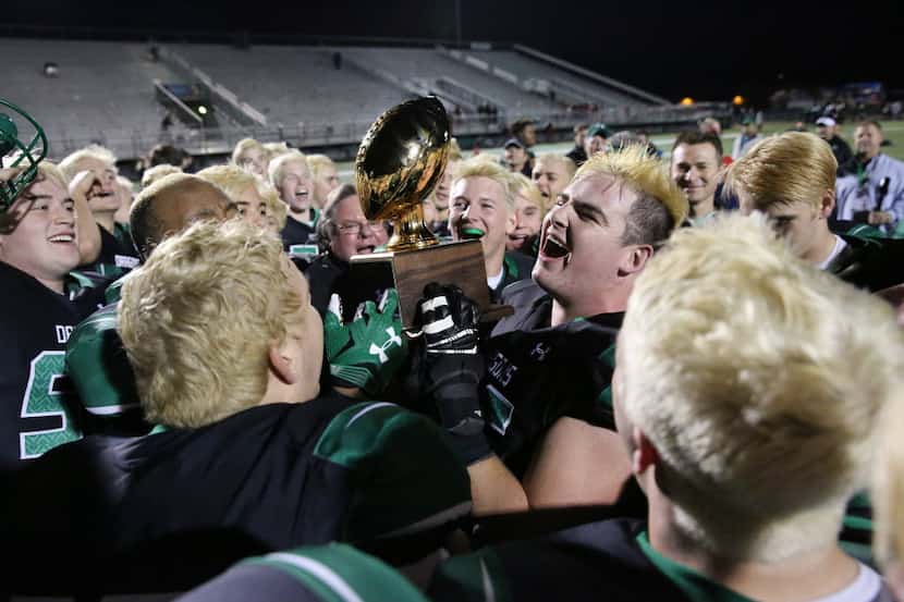 Southlake Carroll offensive lineman Lucas Tribble holds onto the winner's trophy while...
