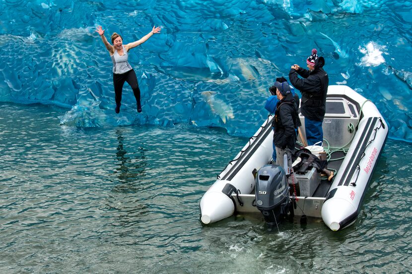 Deckhand Robyn Hutchings dives off an iceberg into the frigid waters of Endicott Arm.