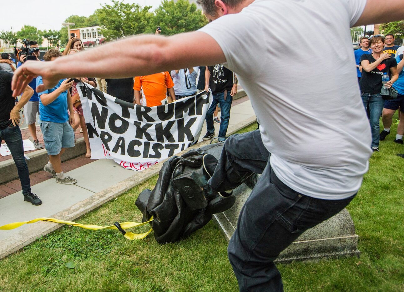 A protester kicks the toppled statue of a Confederate soldier after it was pulled down in...