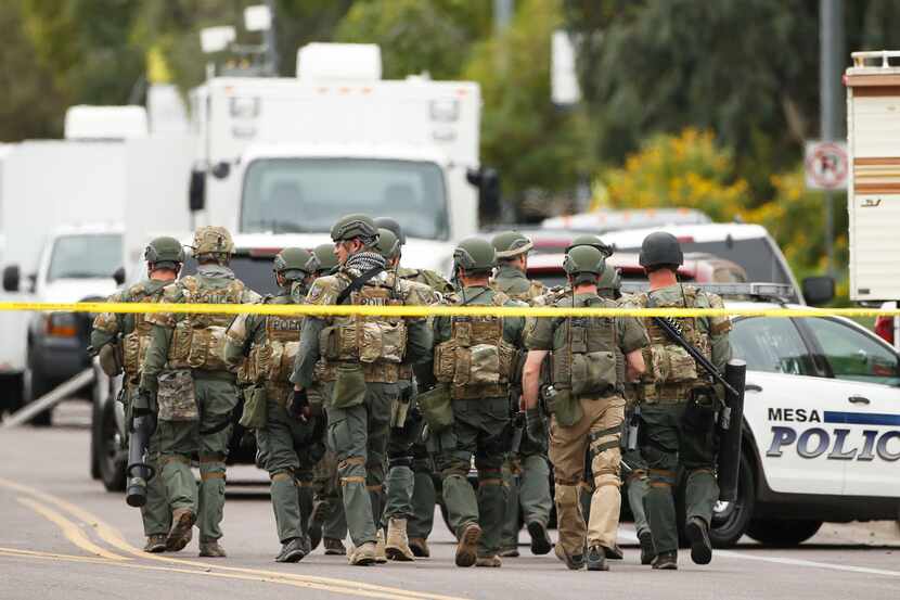A SWAT team walks down the street near Adams Elementary School searching for a gunman on...