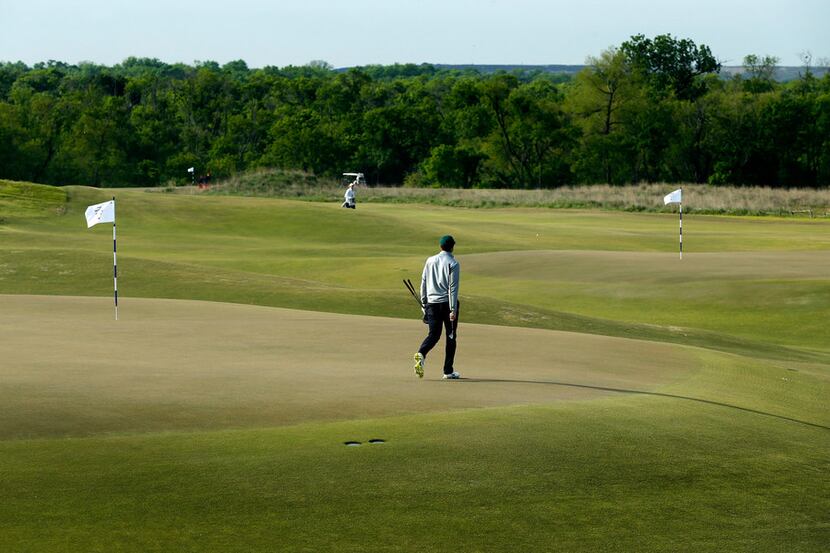 A golfer walks across the 15th green as the 5th green is seen in the background at the new...
