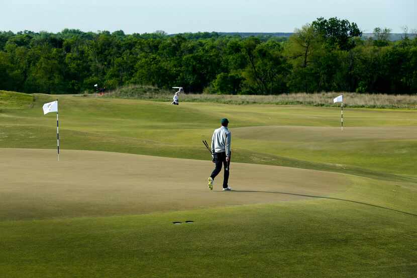 A golfer walks across the 15th green as the 5th green is seen in the background at the new...