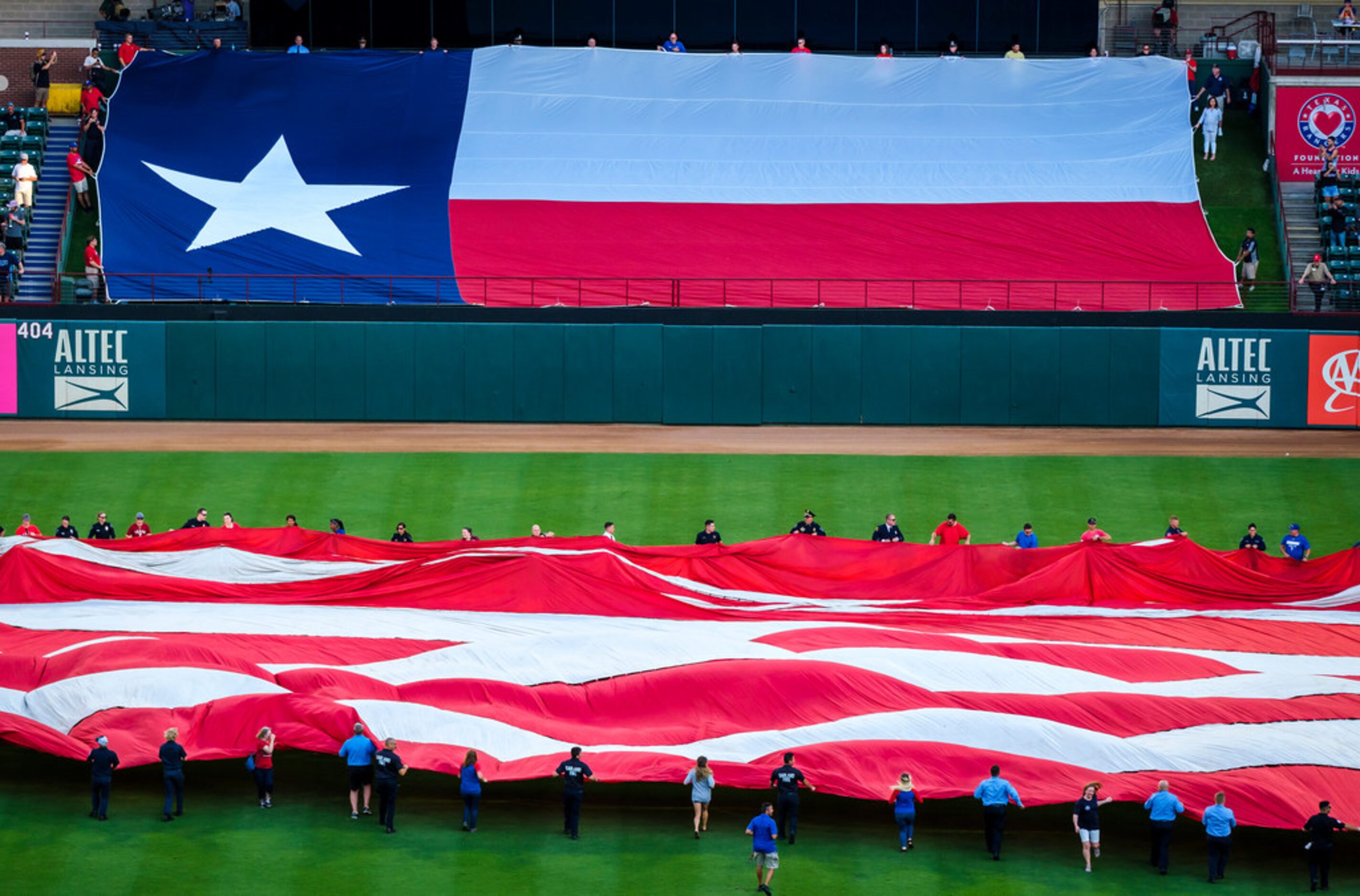 First responders from the Arlington police and fire departments unfurl large US and Texas...