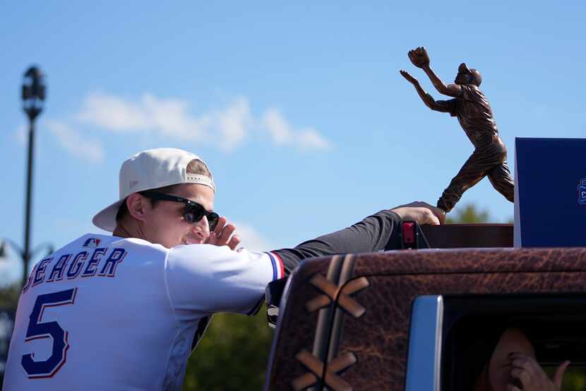 Texas Rangers' Corey Seager rides in the back of a pickup truck by his World Series Most...