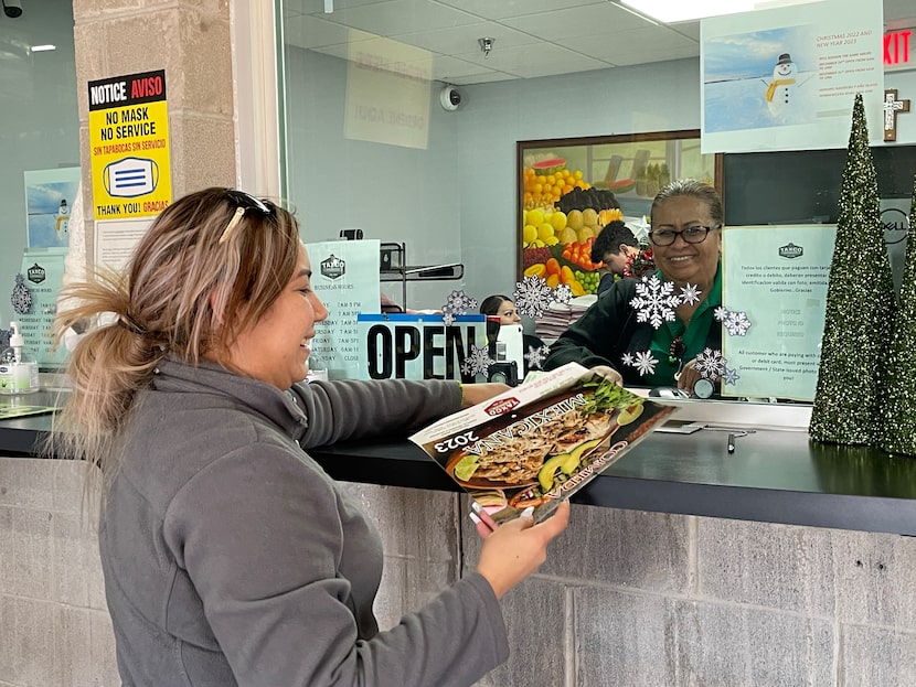 Gabriela Mendoza (izq.) recibe un calendario de manos de Carmen Mendoza (der.), cajera en...