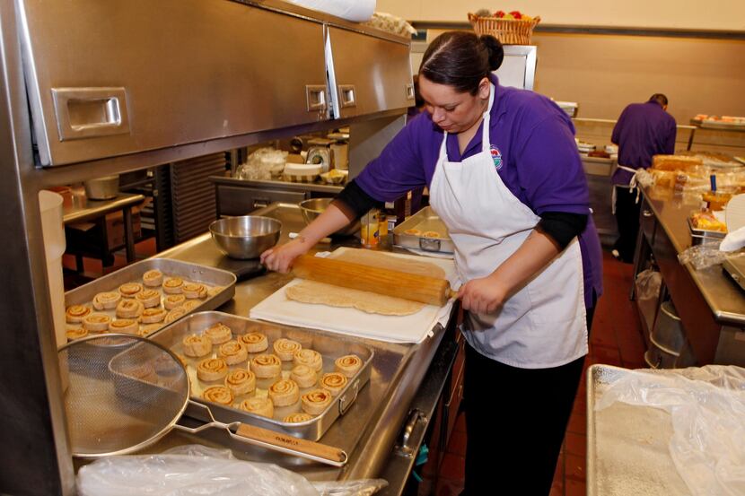 Alexes Garcia makes cinnamon rolls for student's lunch in the kitchen at a middle school in...