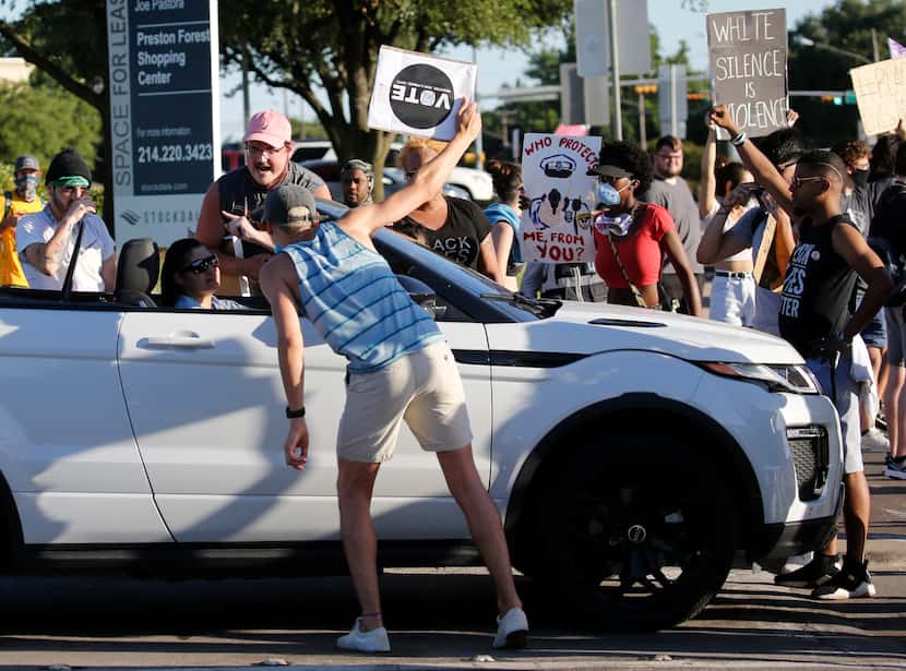 Protesters talk to a driver as they block the intersection of Preston Rd. and Forest Lane in...