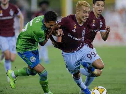 Seattle Sounders' Danny Leyva, left, tangles with Colorado Rapids' Andre Shinyashiki (99)...