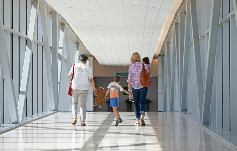 Luke Swofford (second from left), 4, walks on the bridge to the parking garage with his...