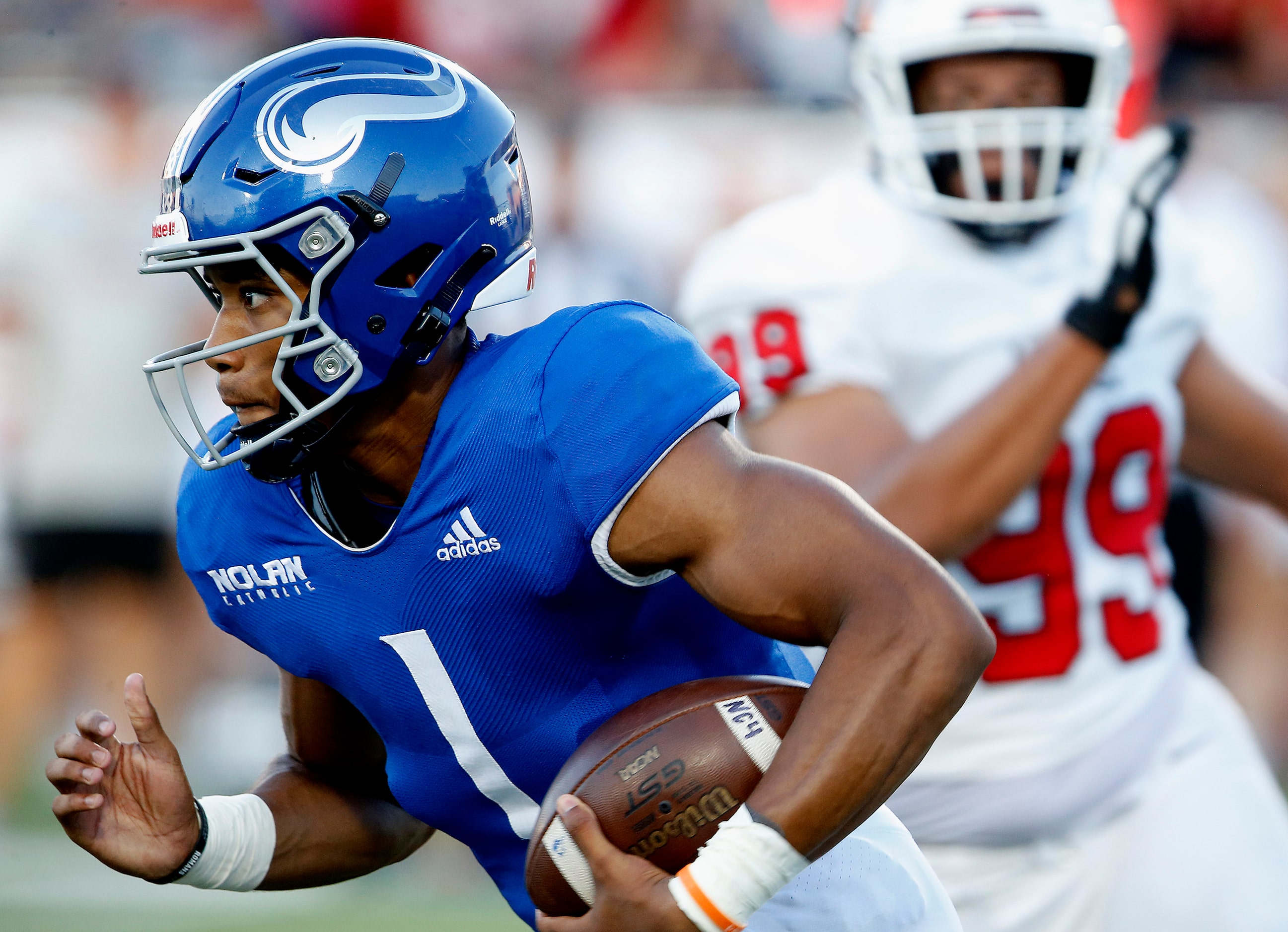 Nolan Catholic High School quarterback Tj Williams (1) carries the ball during the first...