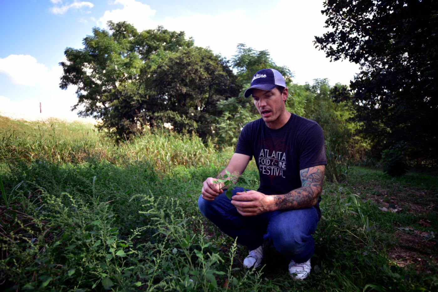Chef Matt McCallister of FT33 restaurant holds a batch of wild spinach as he walks through...