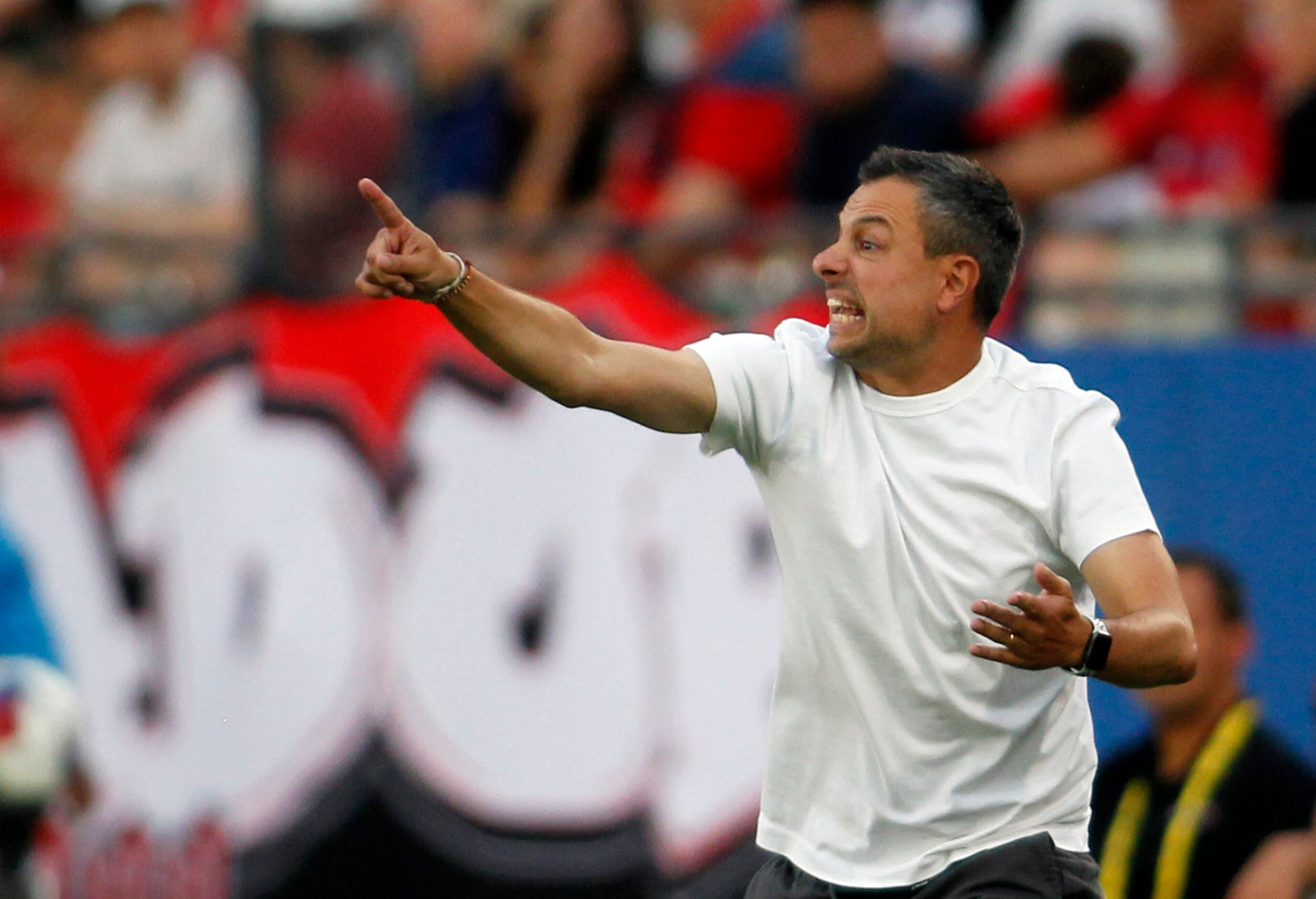 FC Dallas head coach Nico Esteves works to get a message to his players on the field during...