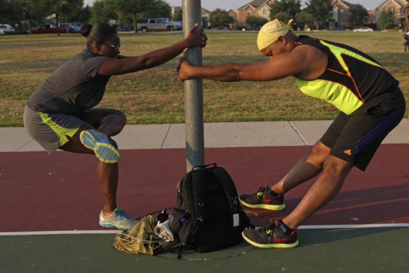M.K. Evans (left) and Kenny Hibbler stretch on a basketball hoop.