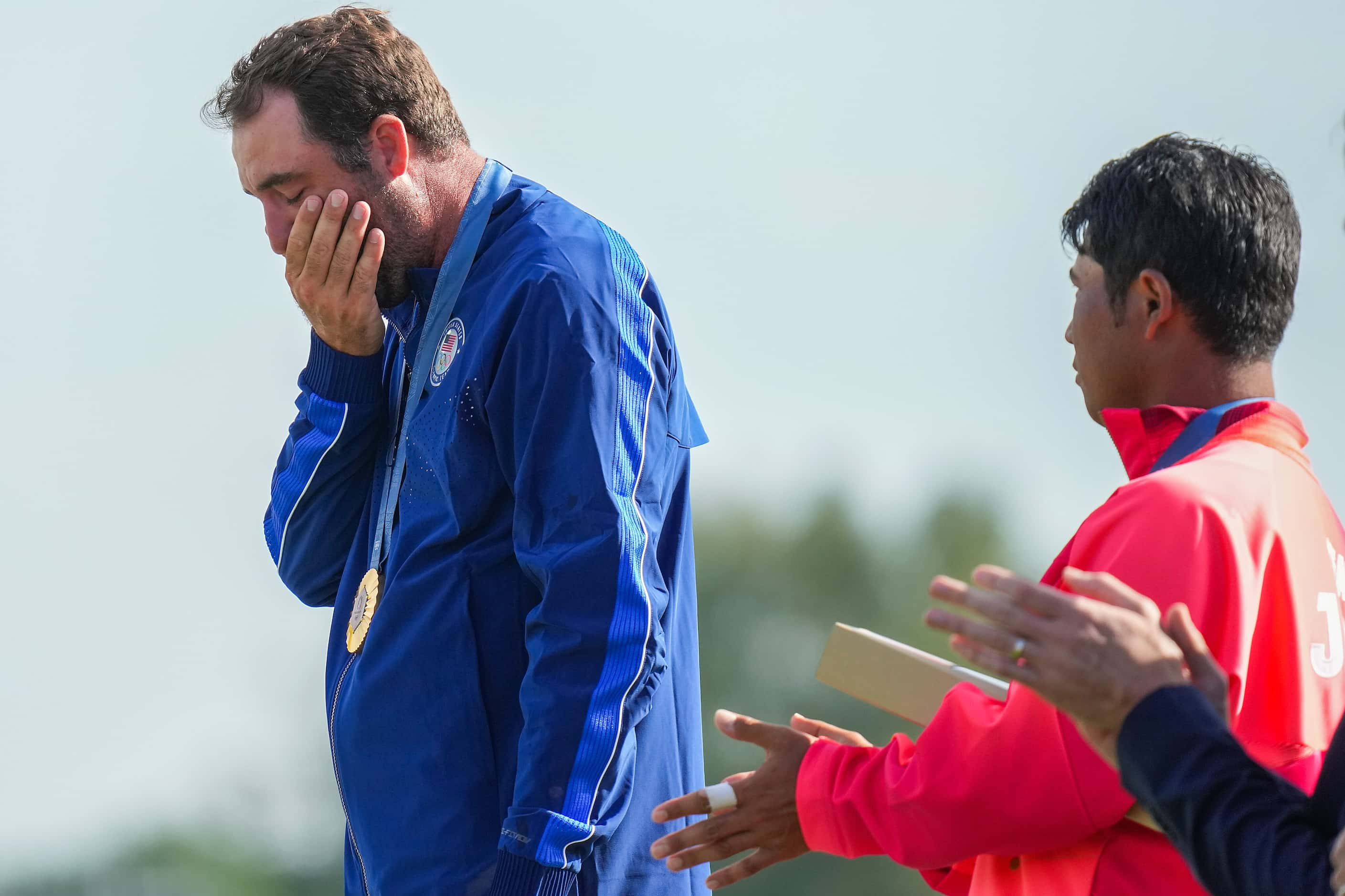 Gold medalist Scottie Scheffler of the United States wipes away tears while the Star...