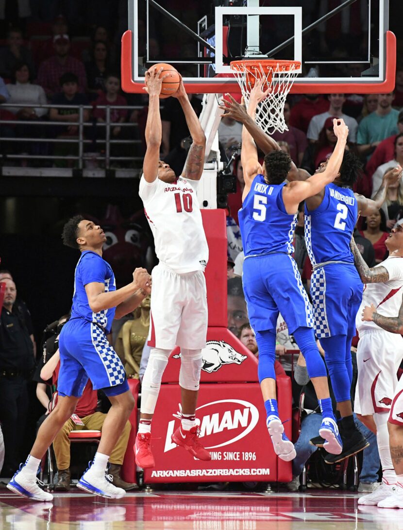 Arkansas' Daniel Gafford comes down with a rebound between Kentucky's P.J. Washington, left,...