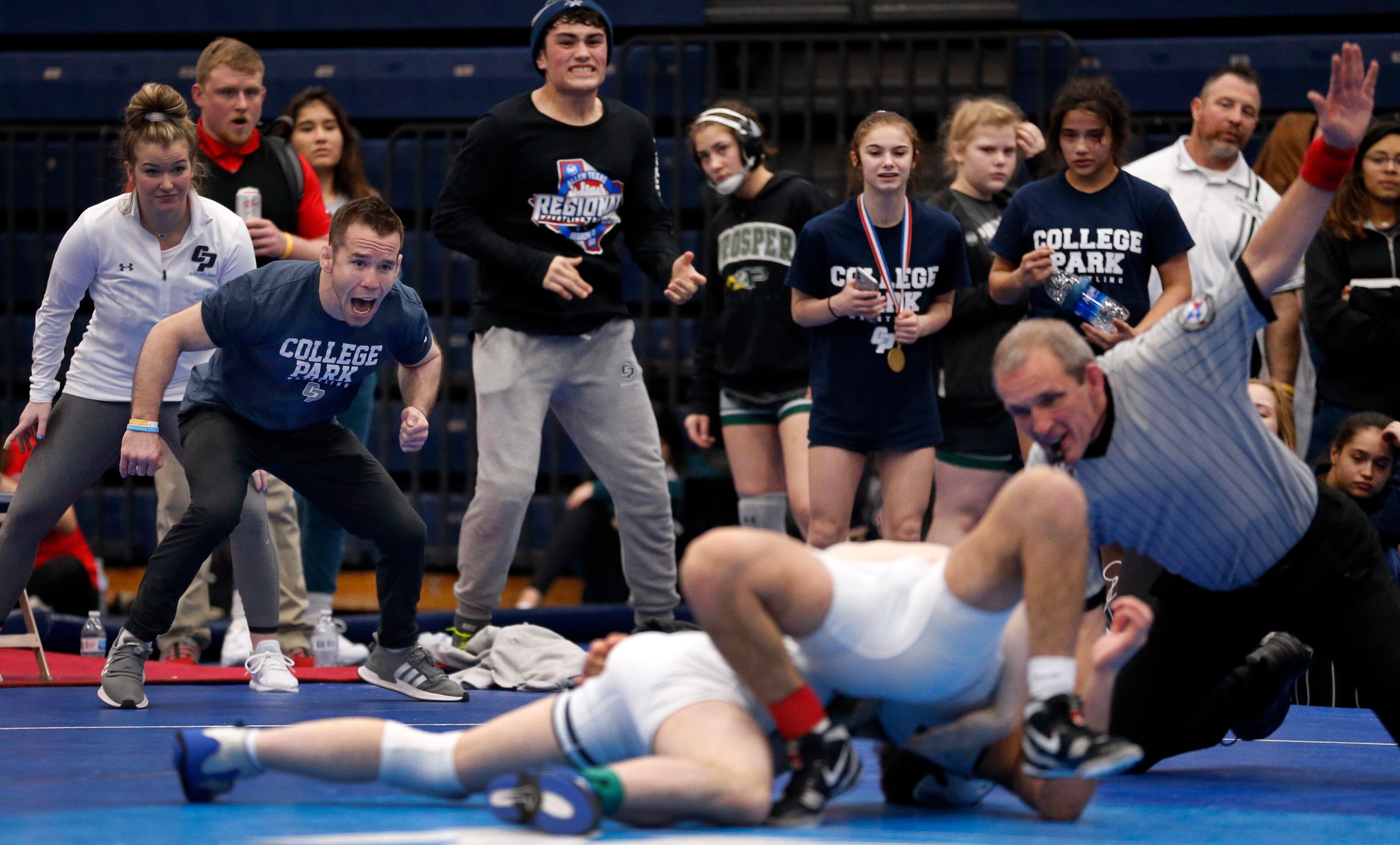 College Park head coach Erik Spjut (yelling, left) and his wrestlers cheer on their teammate...