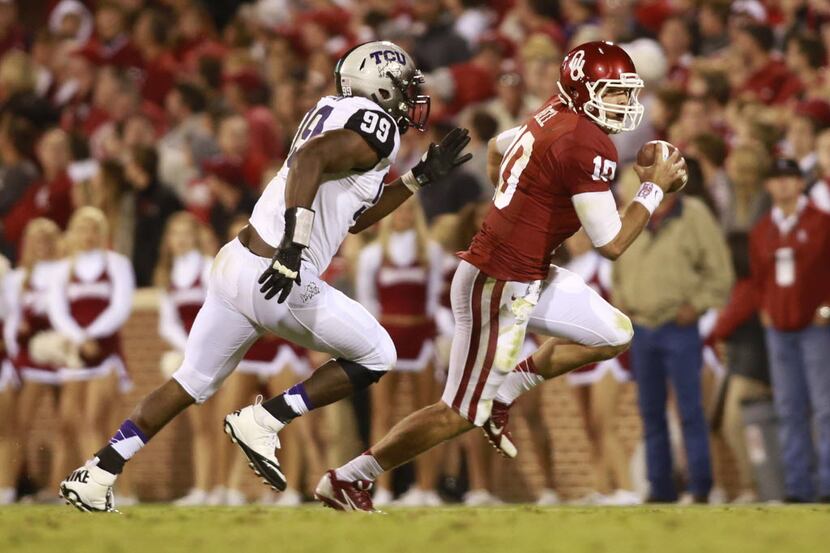 Oklahoma quarterback Blake Bell (10) is chased by TCU defensive lineman Tevin Lawson in the...