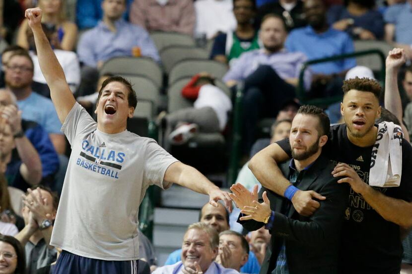 Dallas Mavericks owner Mark Cuban, left, cheers his team on during the second half of an NBA...
