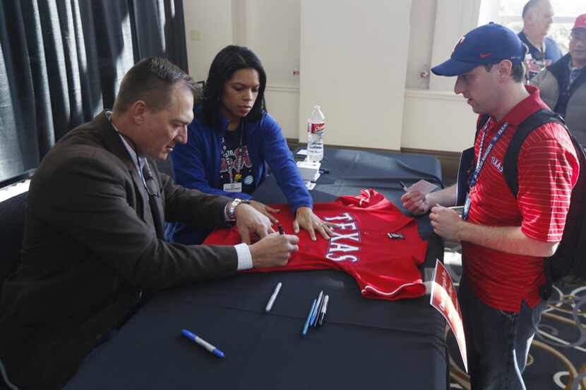 Texas Rangers Manager Jeff Banister signs an autograph on a shirt for Andrew Barnes of...