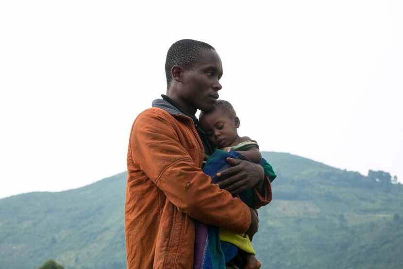 A Congolese man holds his child after he crossed the border from the Democratic Republic of...