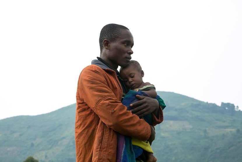 A Congolese man holds his child after he crossed the border from the Democratic Republic of...