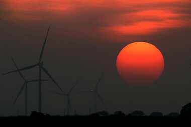 The sun sets at windmill farm in McCook, Texas during a heat wave on Wednesday, July 20,...