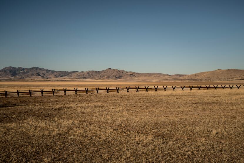 The border fence, here composed of X-shaped barriers, passes through ranching land on the...