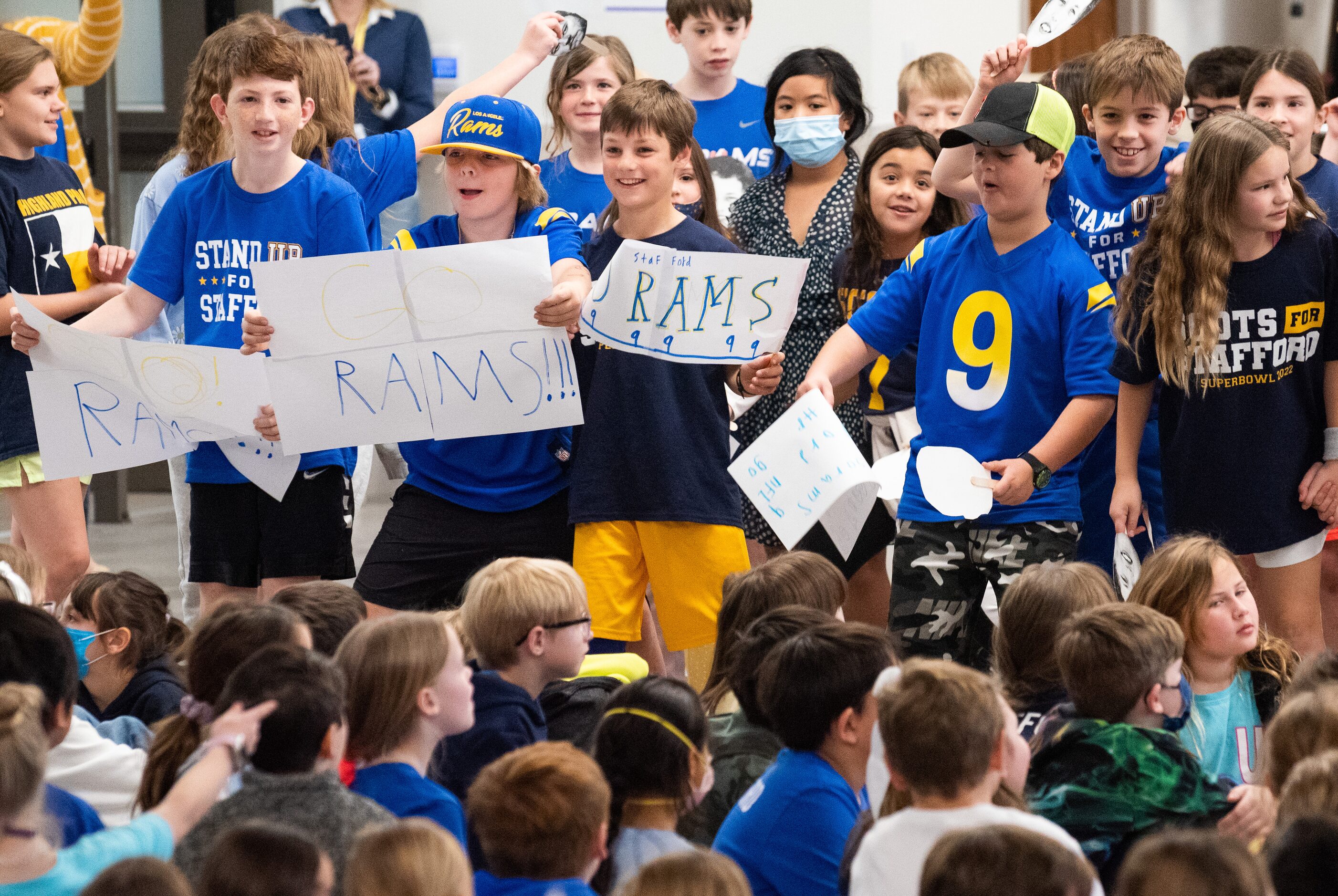 Fourth graders shake signs and wave photo cut-outs as they cheer during a pep rally in...