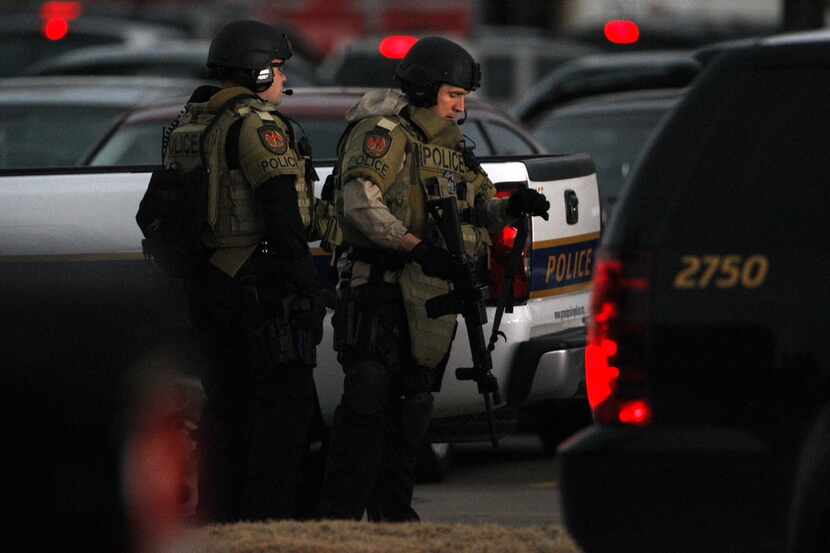 Grand Prairie police officers in full body armor search a parking lot for a suspect after...
